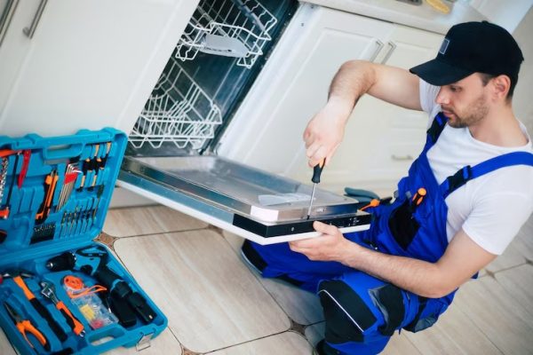 young-modern-serviceman-worker-suit-repairing-dishwasher-domestic-kitchen_283617-2798